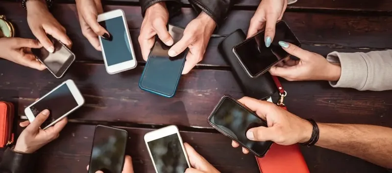 Bir masada akıllı telefon kullanan kişiler sosyal medya yönetimi ipuçları arıyor.