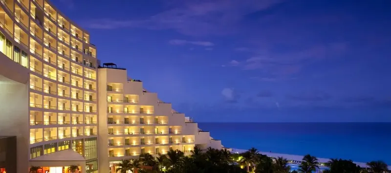 Sahil kenarında lüks bir otel binası, gece vakti ışıklarını yakmış.